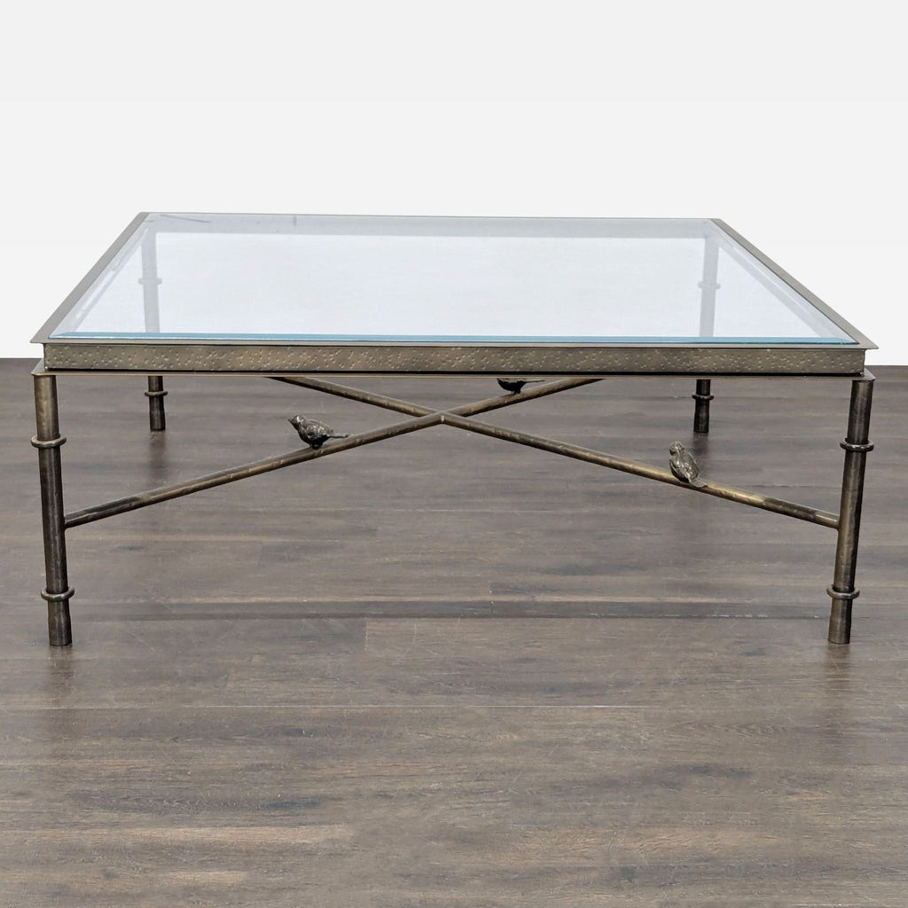 Iron coffee table featuring a hammered bronze apron, glass top, and stretchers decorated with resting birds.  