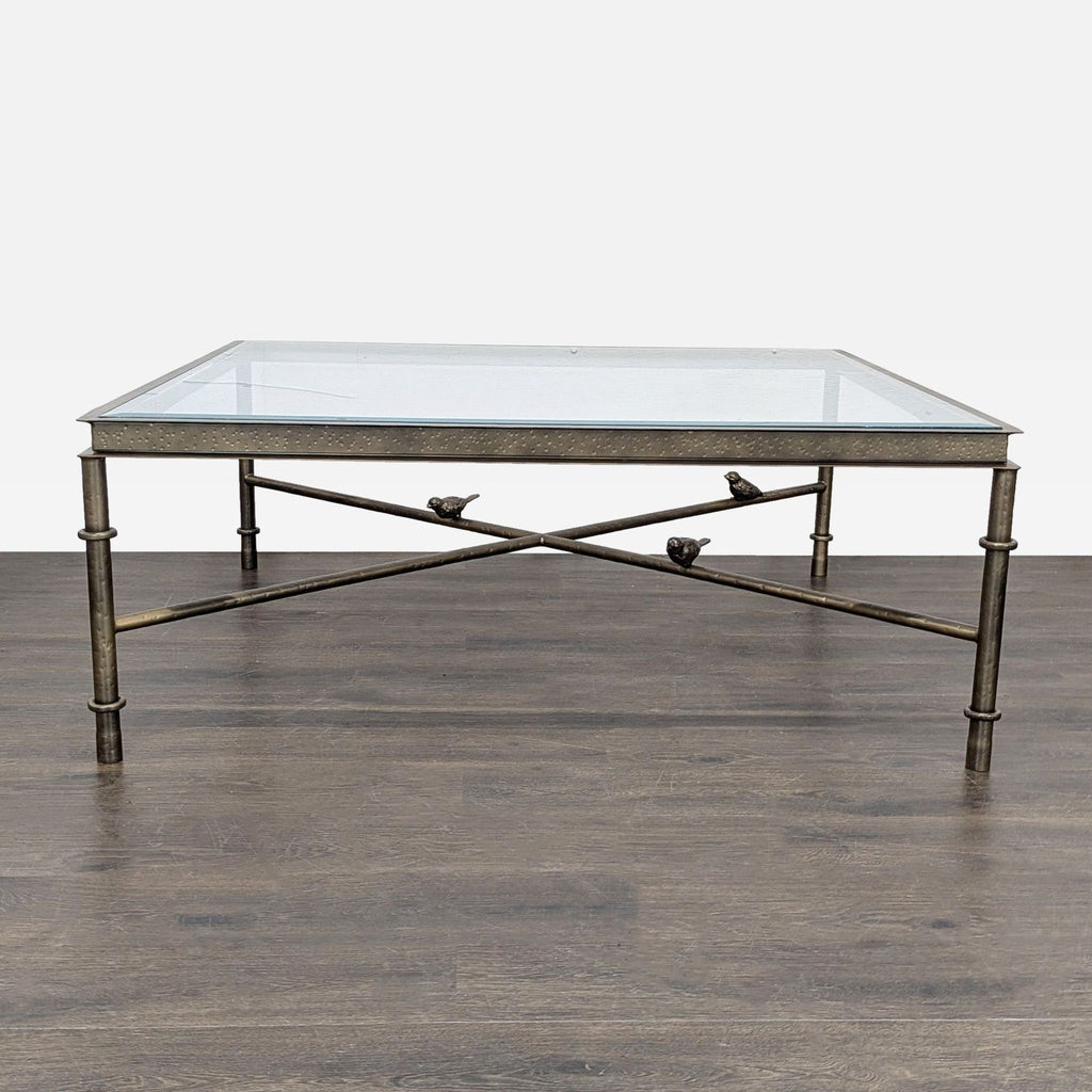 Bronze-finished iron coffee table with hammered apron, beveled glass top, and three bird-adorned stretchers.  