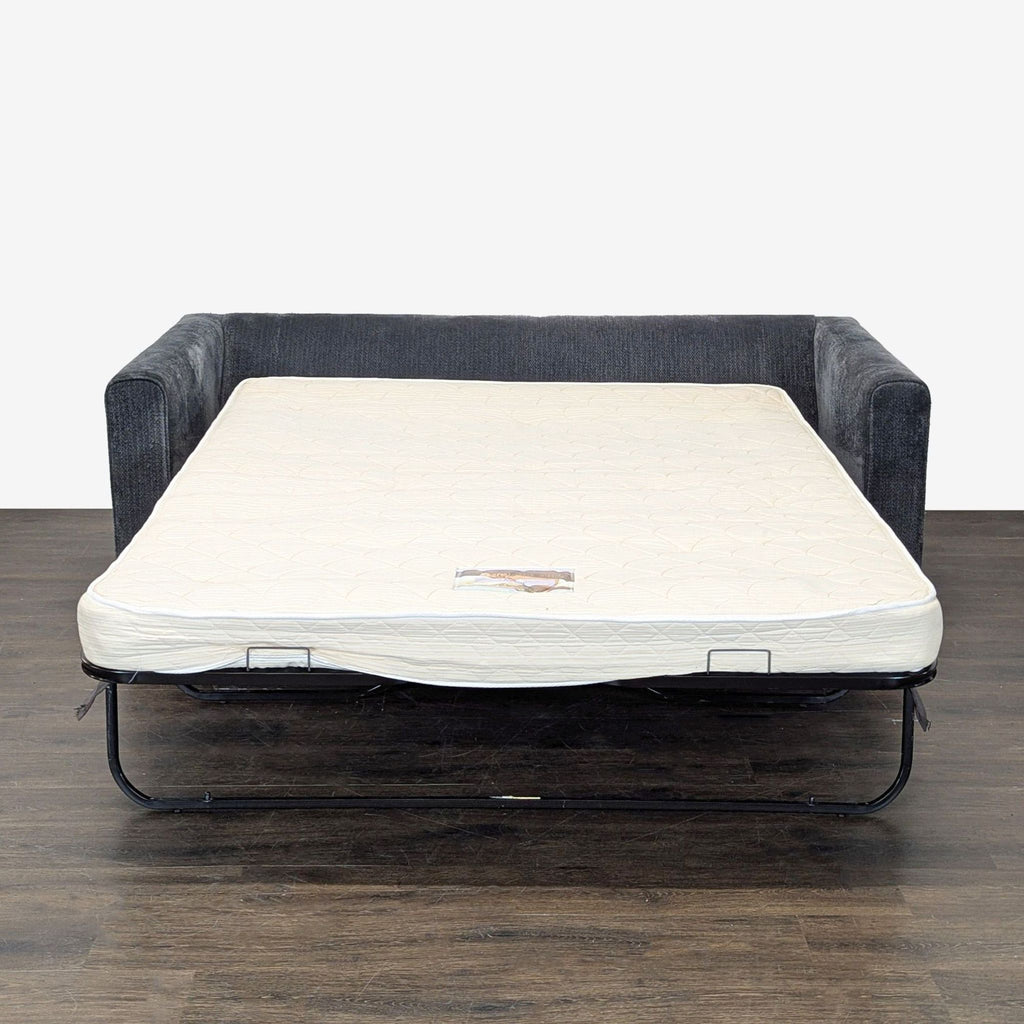 Compact sleeper sofa in dark gray fabric featuring a sturdy frame and supportive cushions for seating or sleeping.  
