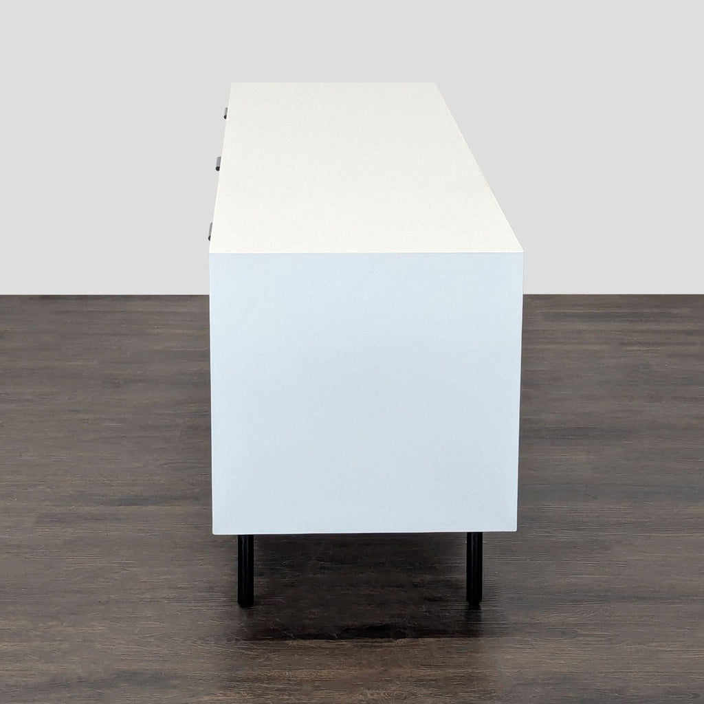Contemporary West Elm media console with textured wooden doors, white body, and sleek metal legs.