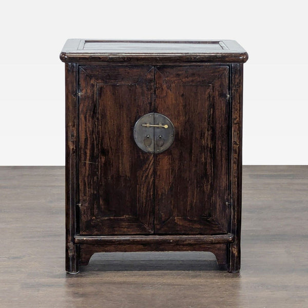 Vintage wooden cabinet with a dark finish, featuring double doors and a round metal lock in the center.