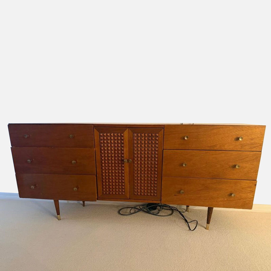 Mid-century modern dresser with six drawers, center cabinet, and brass-accented legs in a warm wood finish.