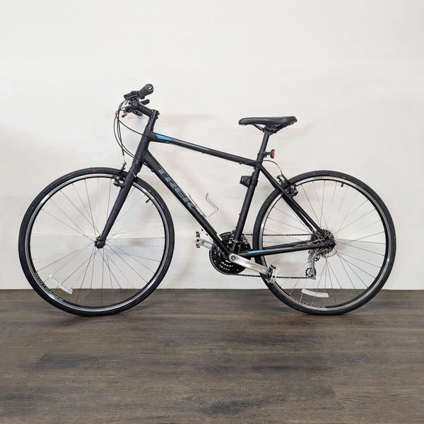 1. Black Trek hybrid bike, lightweight frame, ideal for city rides, displayed indoors on wood floor.  