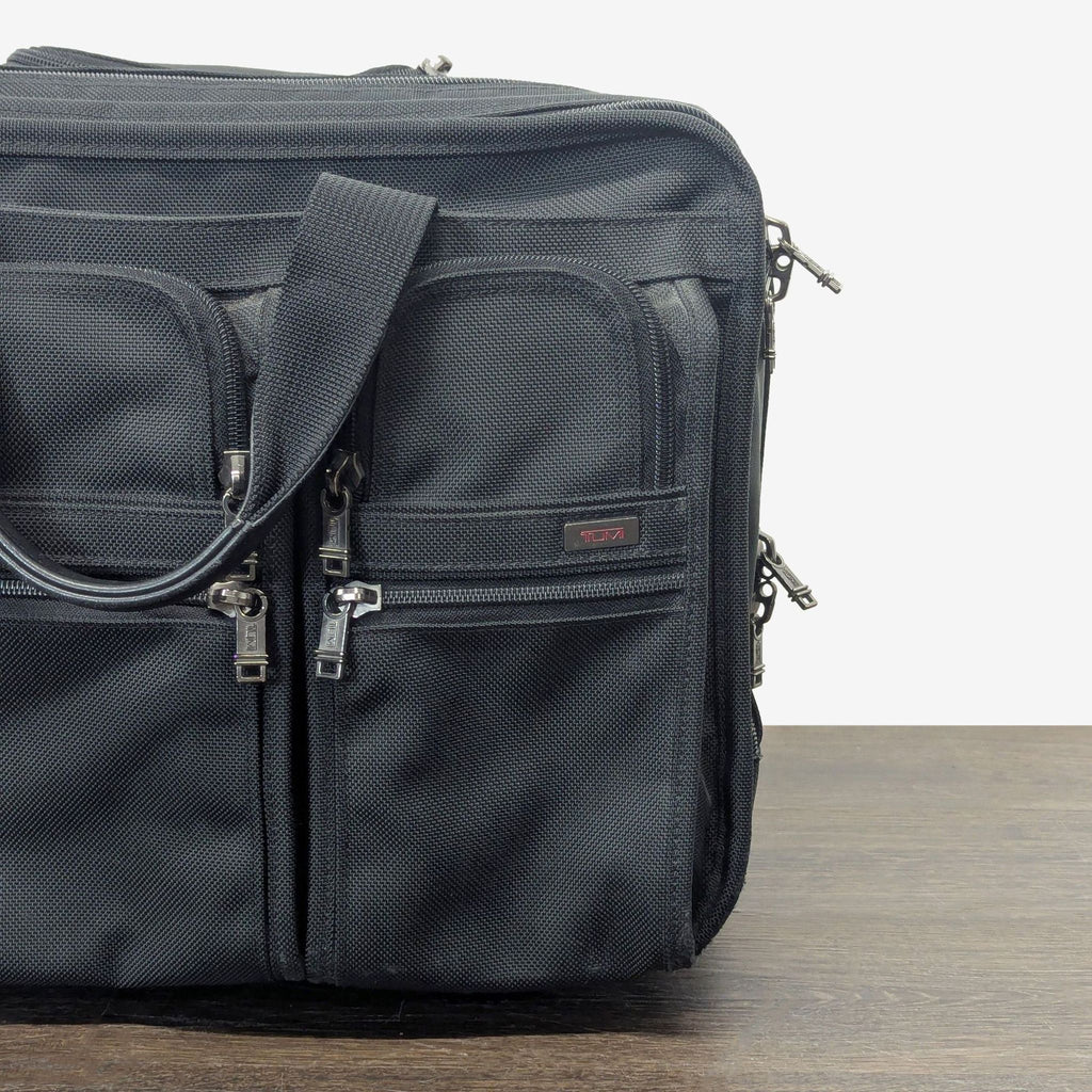 2. Durable Tumi carry-on luggage with a hard shell and branded logo on the front.