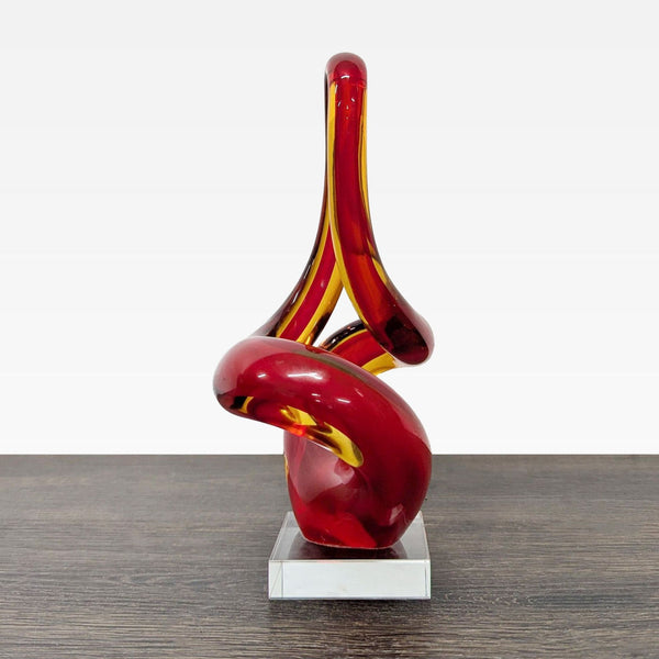 Red and amber twisted glass sculpture on a clear square base, perfect for modern decor.