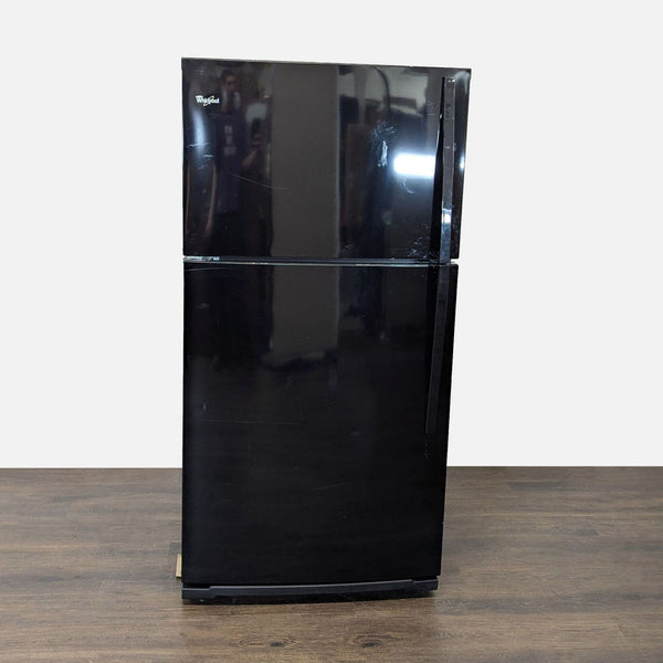 Black Whirlpool top-freezer refrigerator with spacious interior, ideal for home or office use, in good condition.