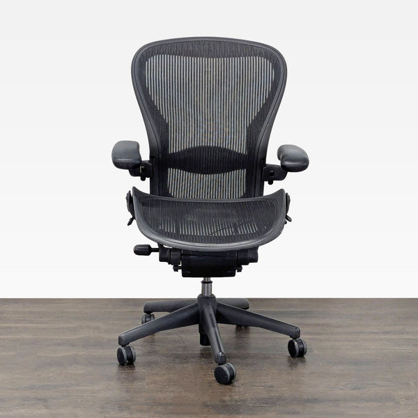 Herman Miller Aeron ergonomic chair with black mesh seat, adjustable armrests, and rolling casters for office comfort.