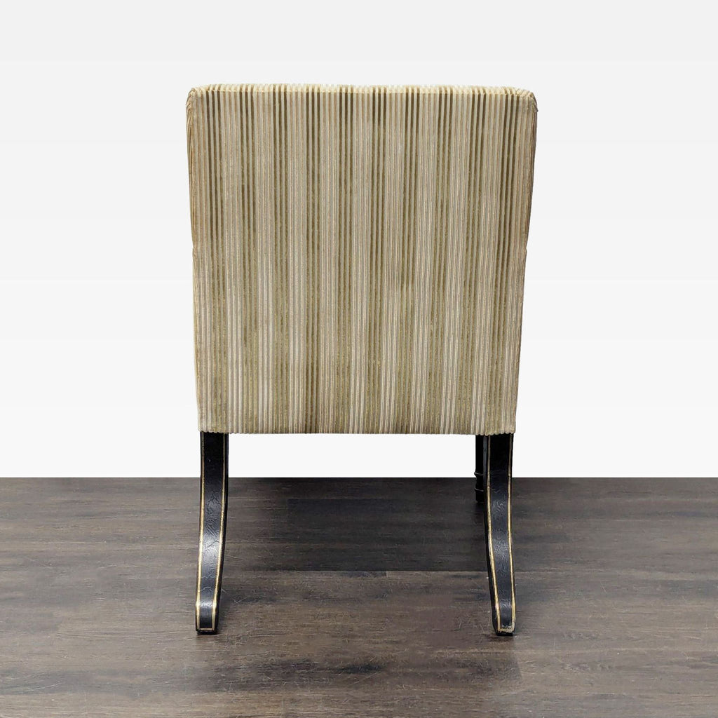 Luxury lounge armchair by Dessin Fournir; gold striped upholstery, lumbar pillow, and black wood legs with gilt accents.