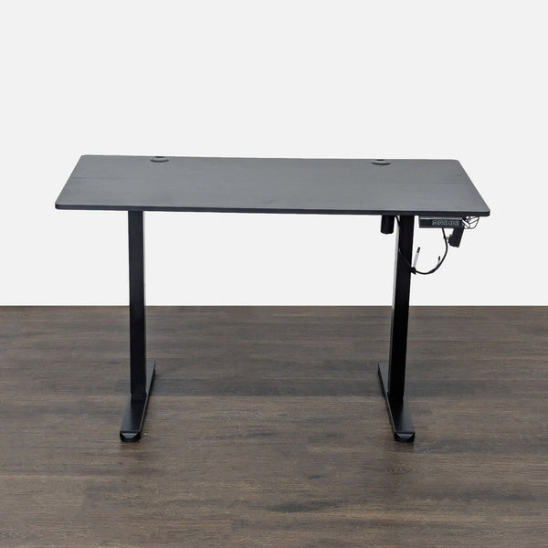 Modern black adjustable desk with electric height controls, cable management, and sturdy metal legs for office use.