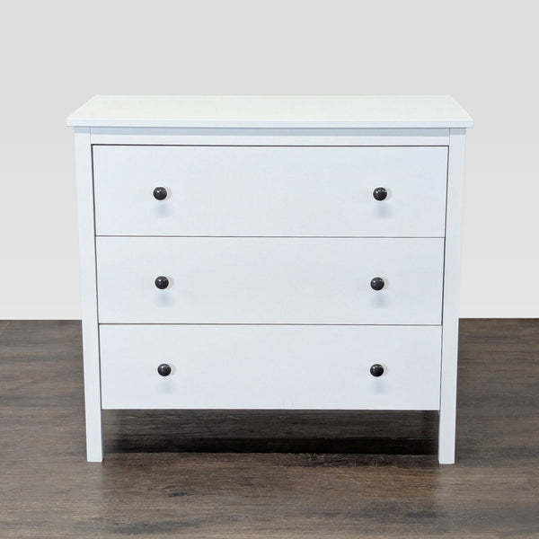 White modern dresser with three drawers and black knobs, ideal for bedroom storage.
