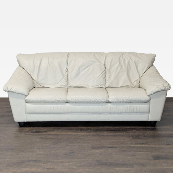 Cream leather 3-seat sofa with wide armrests and modern design, showing minor signs of use.