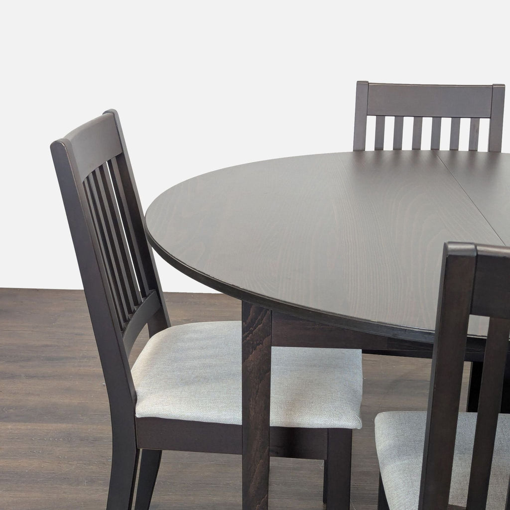 Sleek Ikea dining set featuring a sturdy round table and four matching cushioned chairs for small spaces.