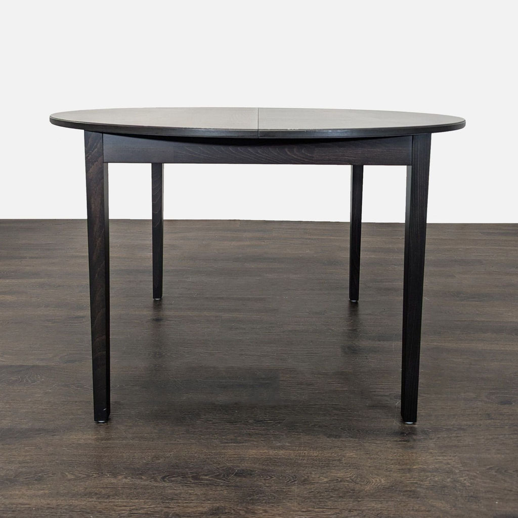 Modern Ikea dining set: round table and four padded chairs with a dark wood finish, perfect for families.  