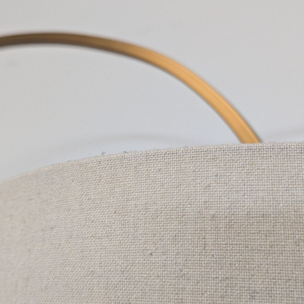 Stylish lighting: Arc lamp with a brass metal body, neutral drum shade, and stable base for elegant decor.