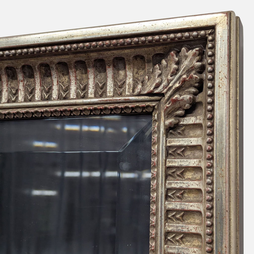 Ornate mirror featuring leaf carvings on corners and perimeter beading.  