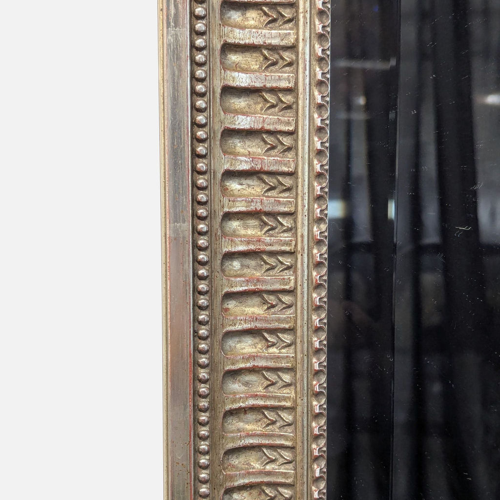 Elegant mirror with beaded edges and leaf designs accenting each corner.
