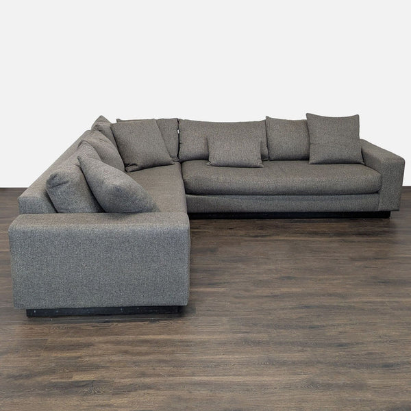 Modern gray L-shaped Rene Cazares sectional with wide armrests and plush cushions for comfortable, spacious seating.