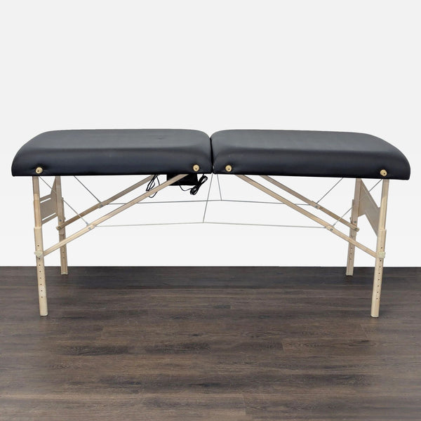Earthlite Vibra-Therm massage table with black padded surface and sturdy wooden frame, folded out for use.