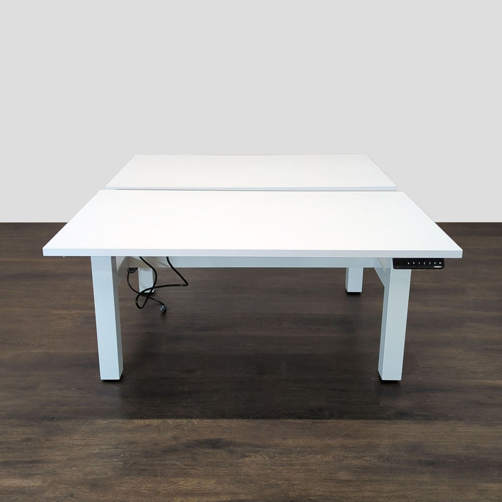 Dual-surface Poppin desk with electric height adjustment, ideal for shared offices; sleek white design and sturdy metal legs.  