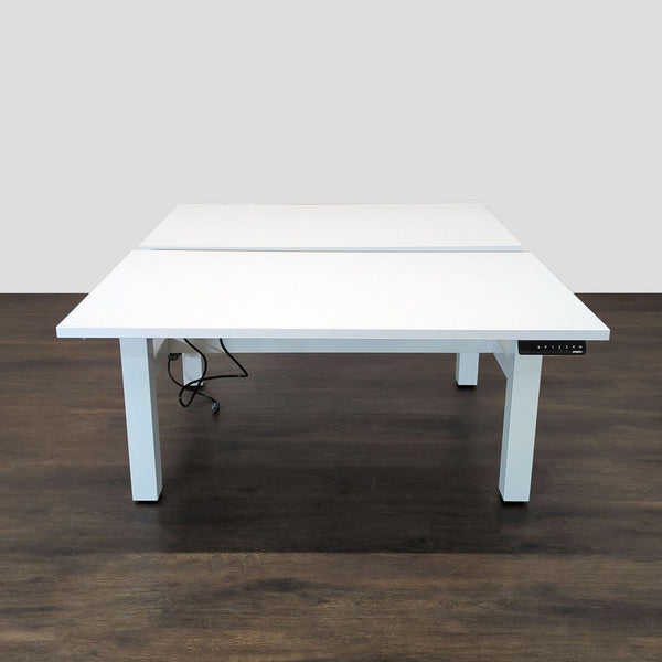Dual-surface Poppin desk with electric height adjustment, ideal for shared offices; sleek white design and sturdy metal legs.  