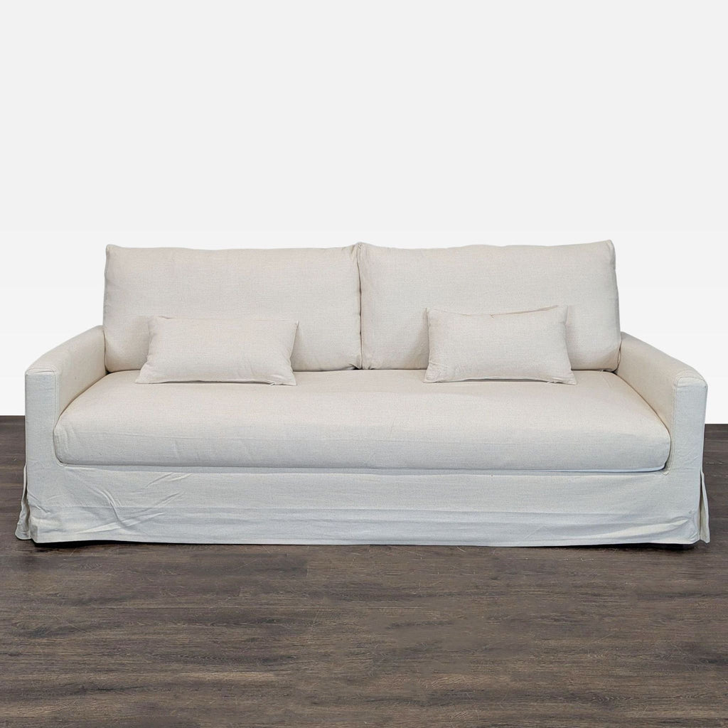 Ikea beige 3-seat sofa with simple design, two backrest cushions, and two smaller pillows for comfort.