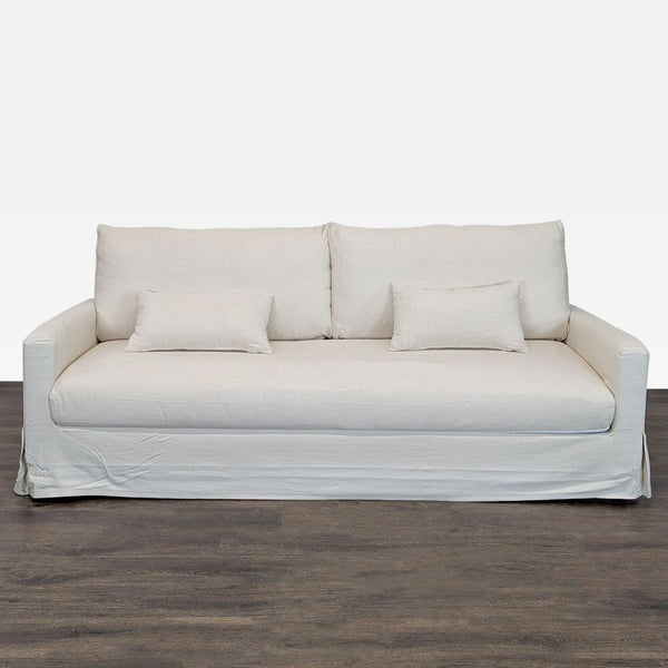 Ikea beige 3-seat sofa with simple design, two backrest cushions, and two smaller pillows for comfort.