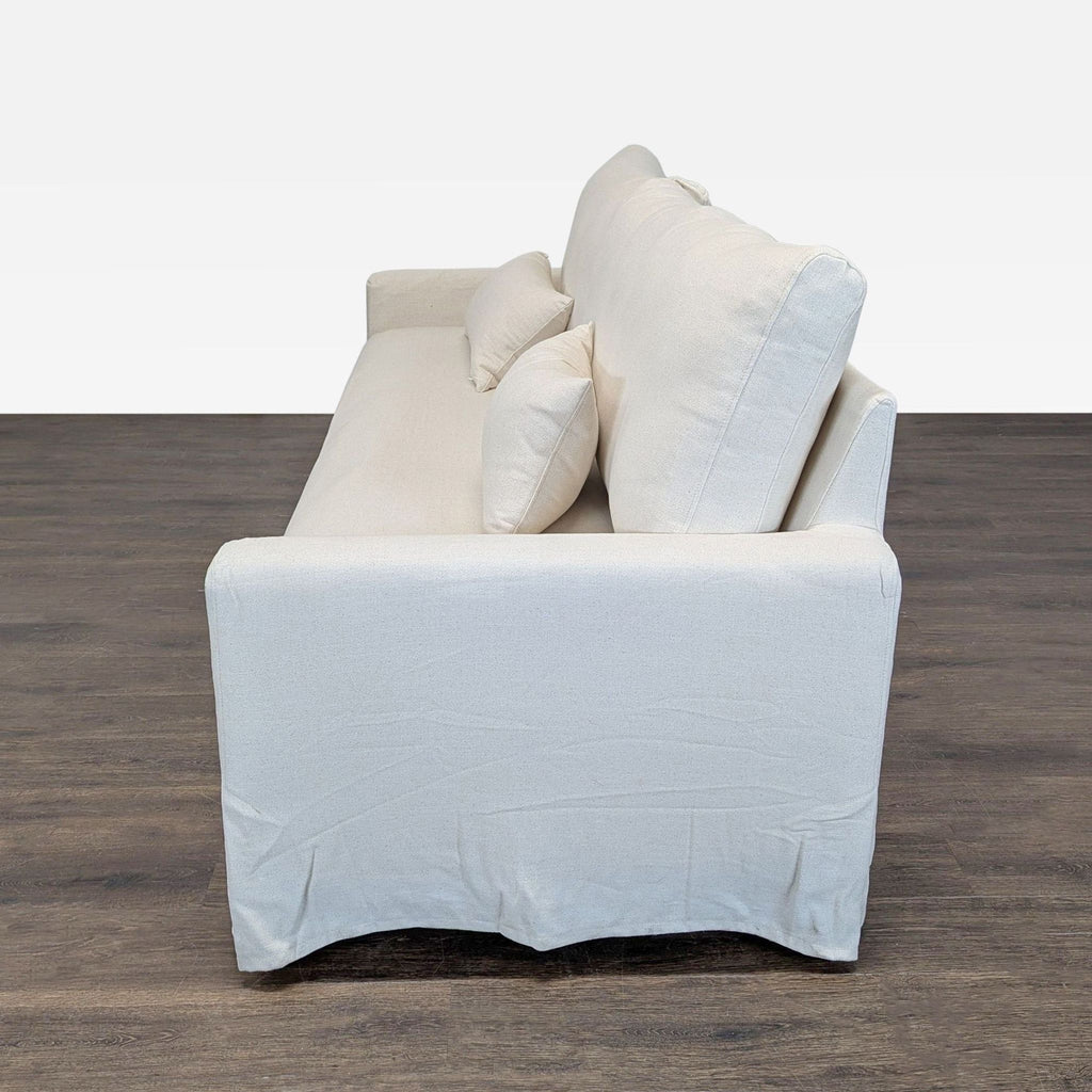 Neutral Ikea 3-seat sofa with clean lines, matching back cushions, and extra pillows, ideal for living rooms.