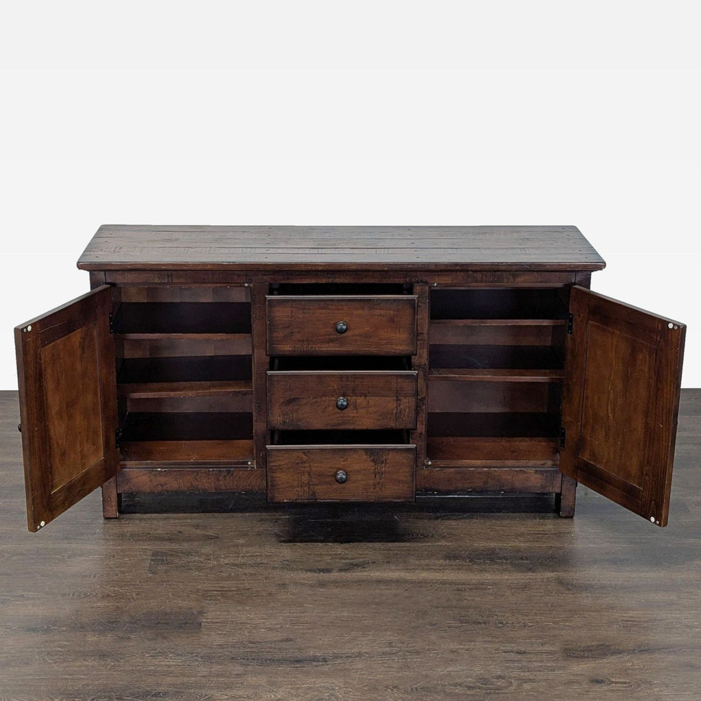 Rustic wood sideboard by Pottery Barn featuring planked construction, central drawers, and side cabinets.