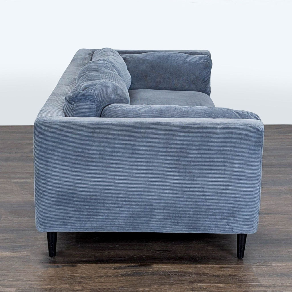 3. Side profile showing the thick cushioned arm and backrest of the blue 3-seat Moe's Home Collection sofa.