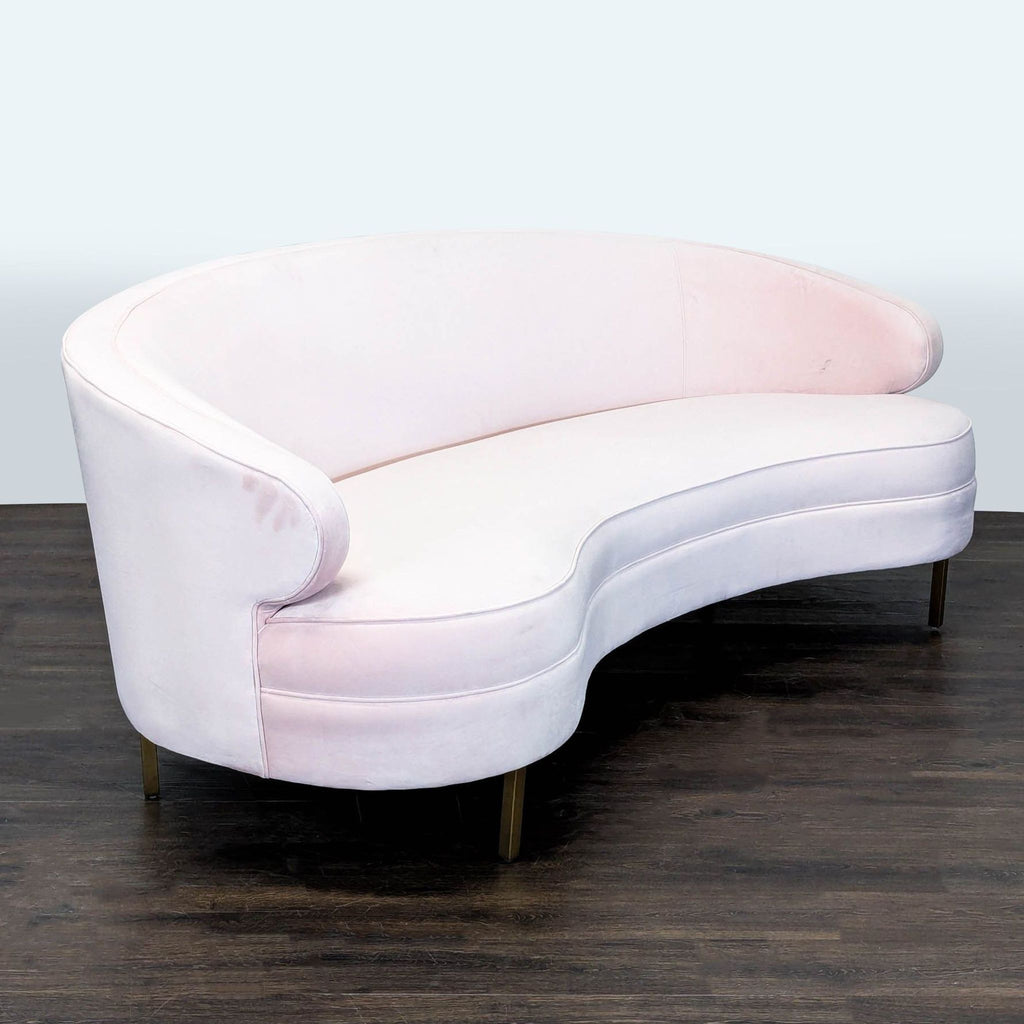 Modern Safavieh sofa featuring soft pink velvet, a unique curved shape, and sleek gold metal legs for style.  