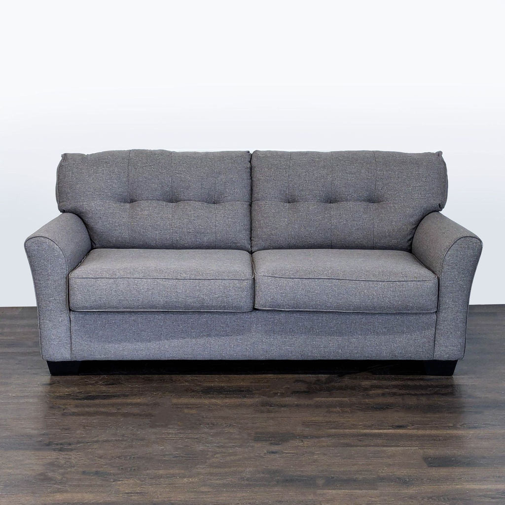 Ashley Furniture gray sleeper sofa with tufted back, seats 2–3, converts easily to a bed for guests.