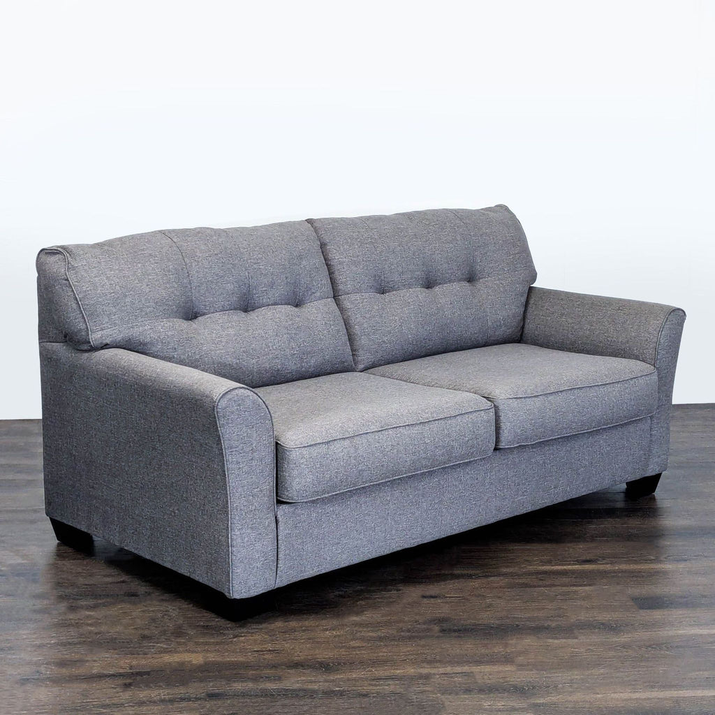 Tufted-back Ashley Furniture sleeper sofa, gray fabric, seats three, folds out to bed for added convenience.