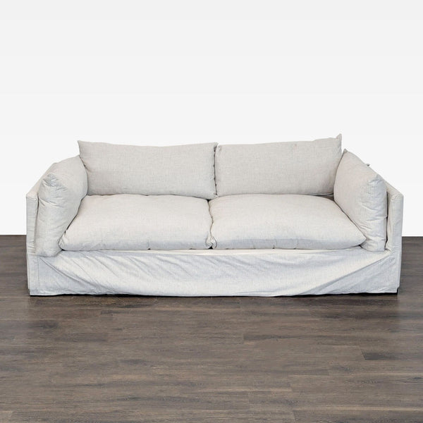 Modern Four Hands loveseat with light slipcover fabric, wide arms, and plush, deep seating for comfort.