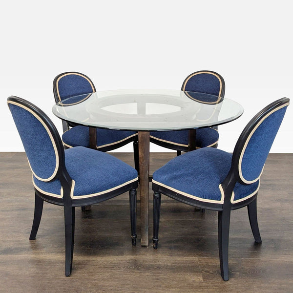 Round glass-top dining set with four blue-upholstered chairs featuring cream trim and black frames.  