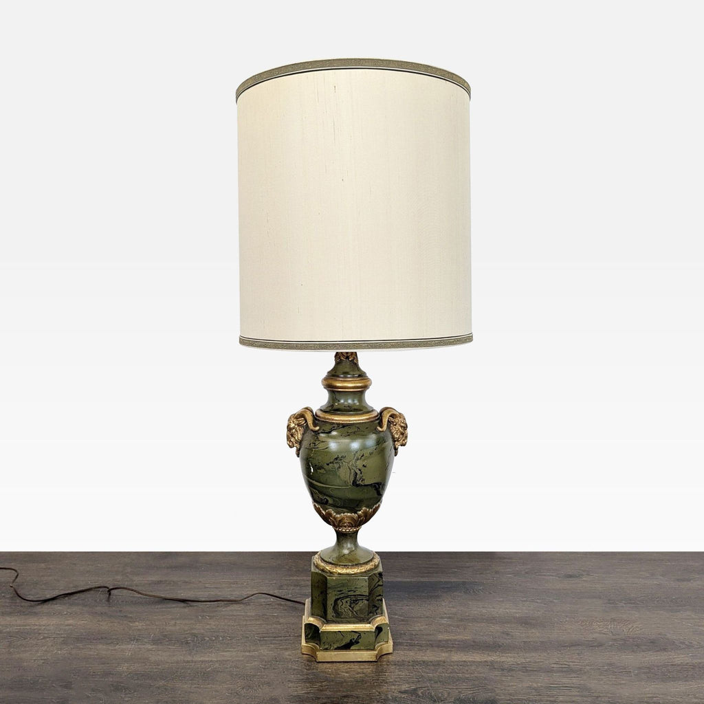 Elegant lamp in mottled olive green with gilded accents, ram head handles, leafy details, and a vintage cream shade.