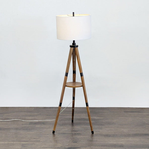 Modern floor lamp with wood tripod base, white drum shade, and a handy built-in shelf from Target.