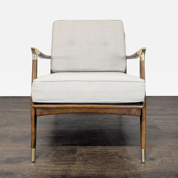 Front view of an Anthropologie lounge chair with beige cushions, wooden frame, and brass accents.