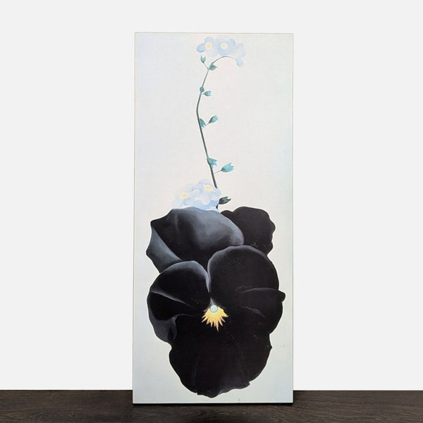 Georgia O'Keeffe print of a bold black pansy surrounded by forget-me-nots on a light background.