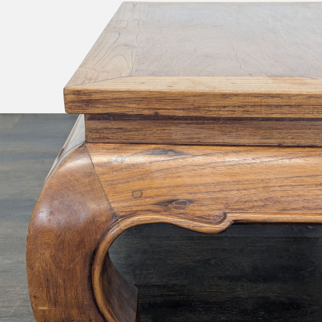 3. Detailed corner view of a wooden coffee table, showcasing the wood grain and the sculpted curve of the leg.
