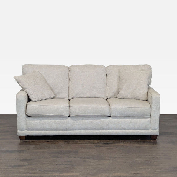 La-Z-Boy 3-seat sofa with light beige fabric, plush cushions, and matching throw pillows on wood legs.  