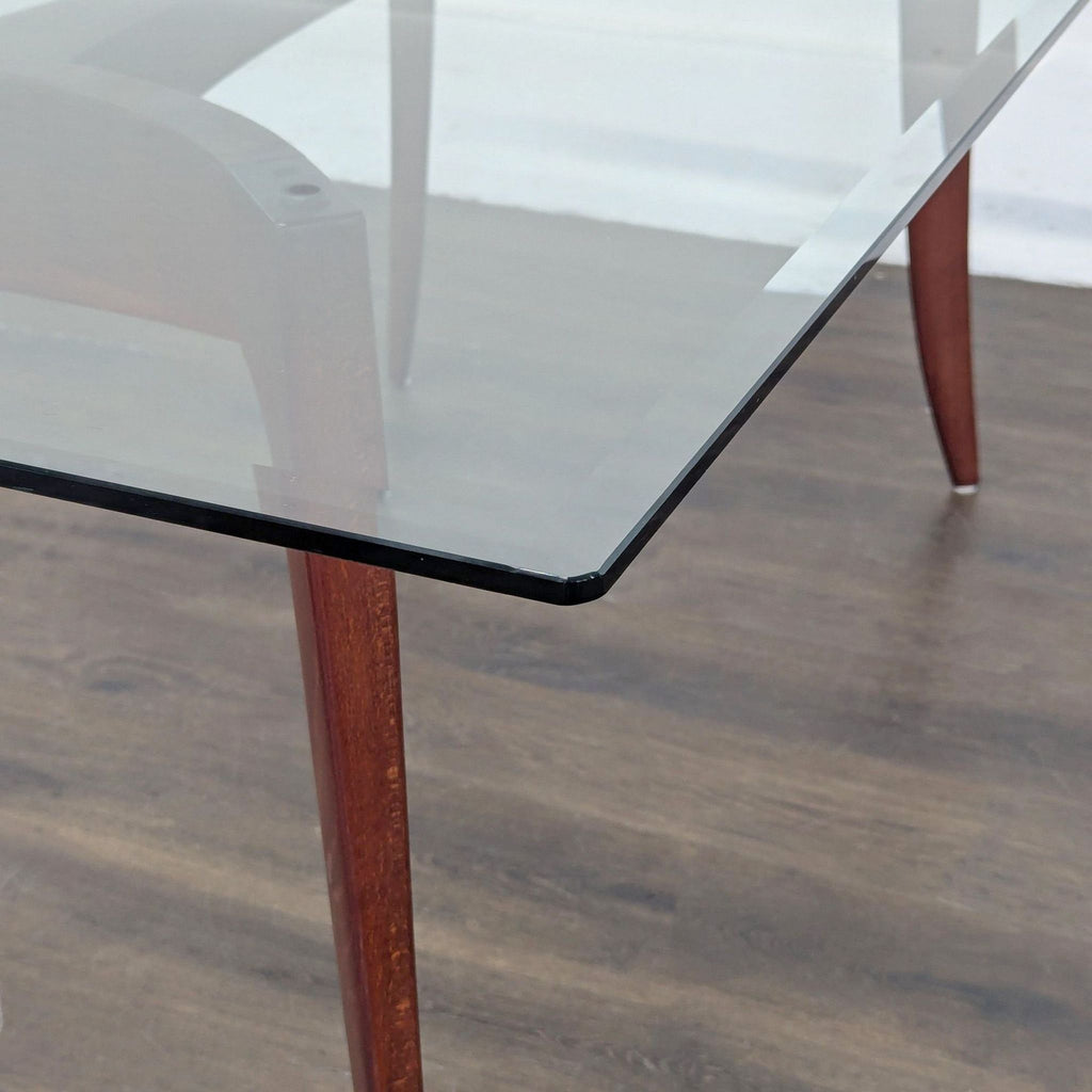 3. Sleek Z Gallerie dining table with a wooden base supporting a beveled glass tabletop.