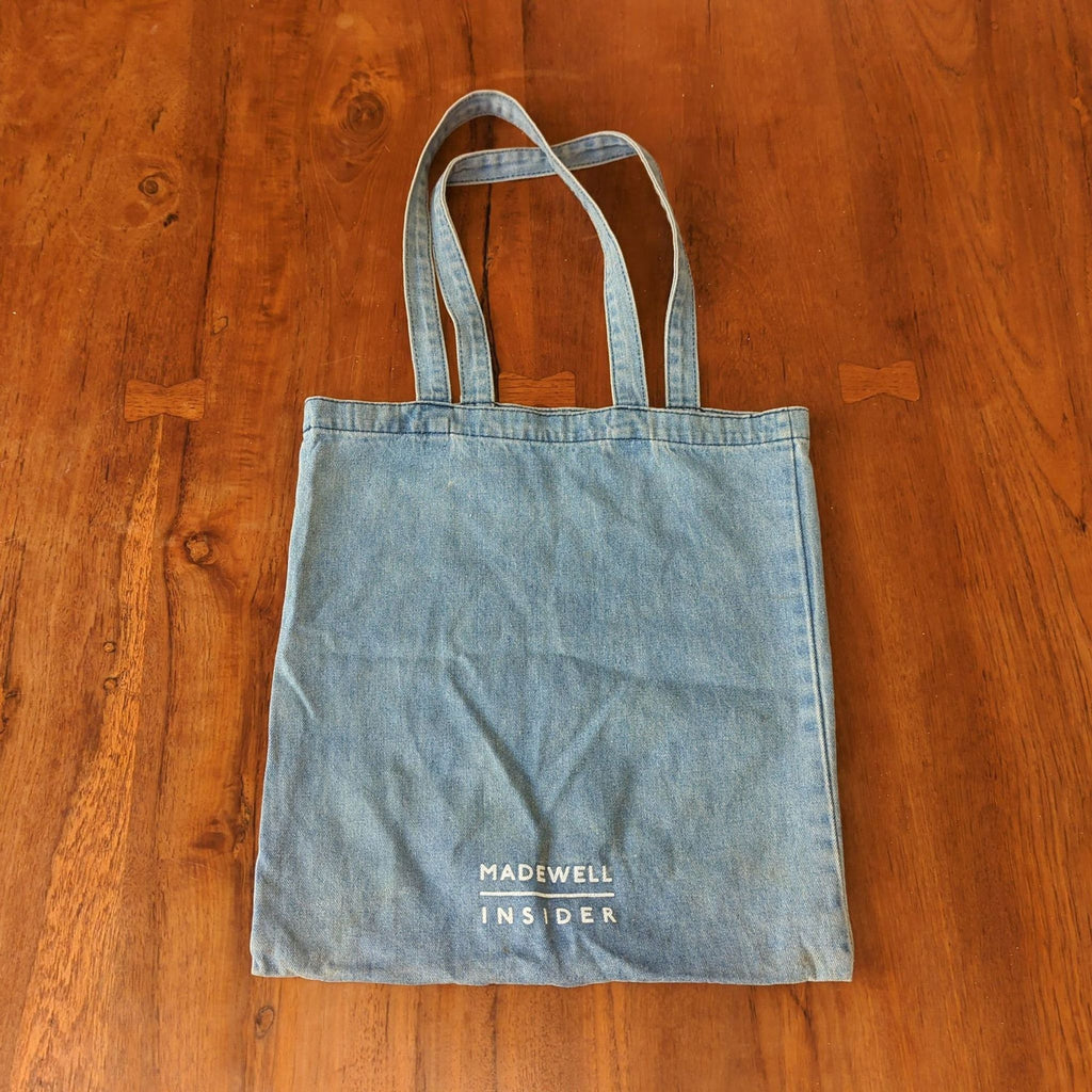 Blue denim Madewell purse featuring a front smiley face and wide handles, perfect for daily use.