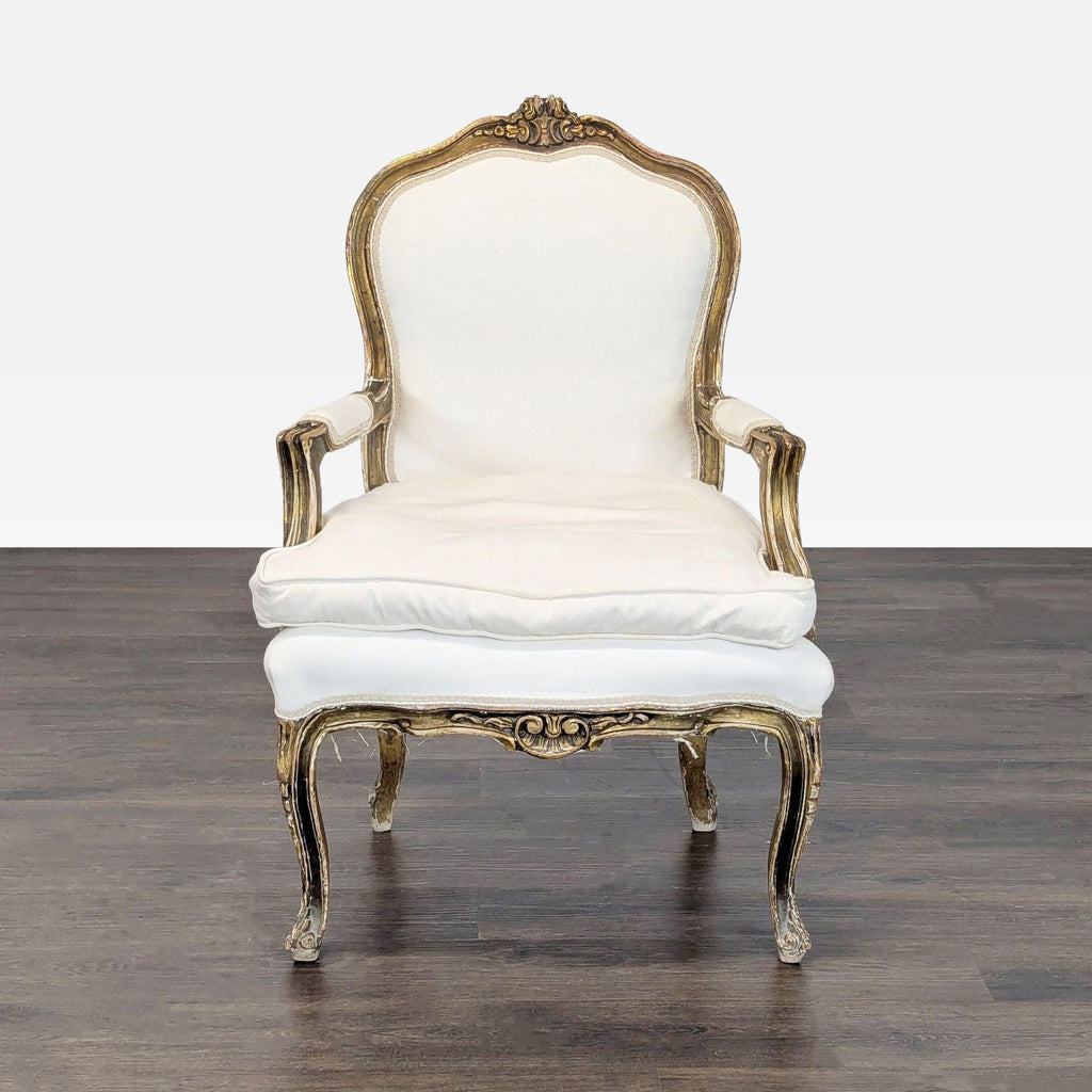 Vintage armchair with gold-trimmed wood frame and white upholstery, featuring elegant carved details.  