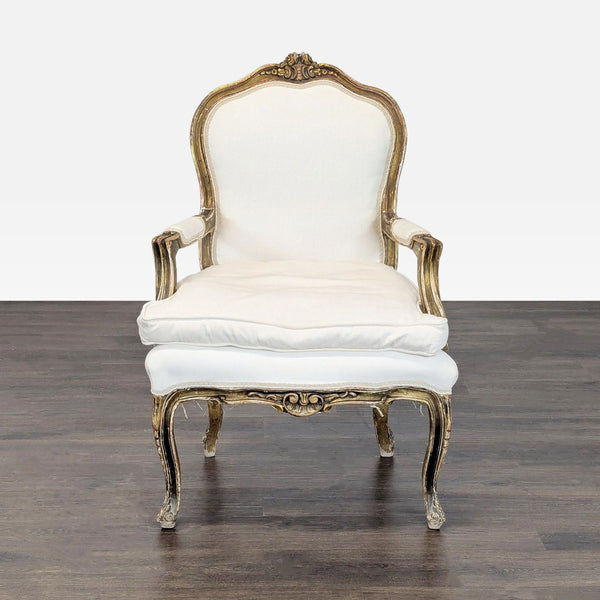 Vintage armchair with gold-trimmed wood frame and white upholstery, featuring elegant carved details.  