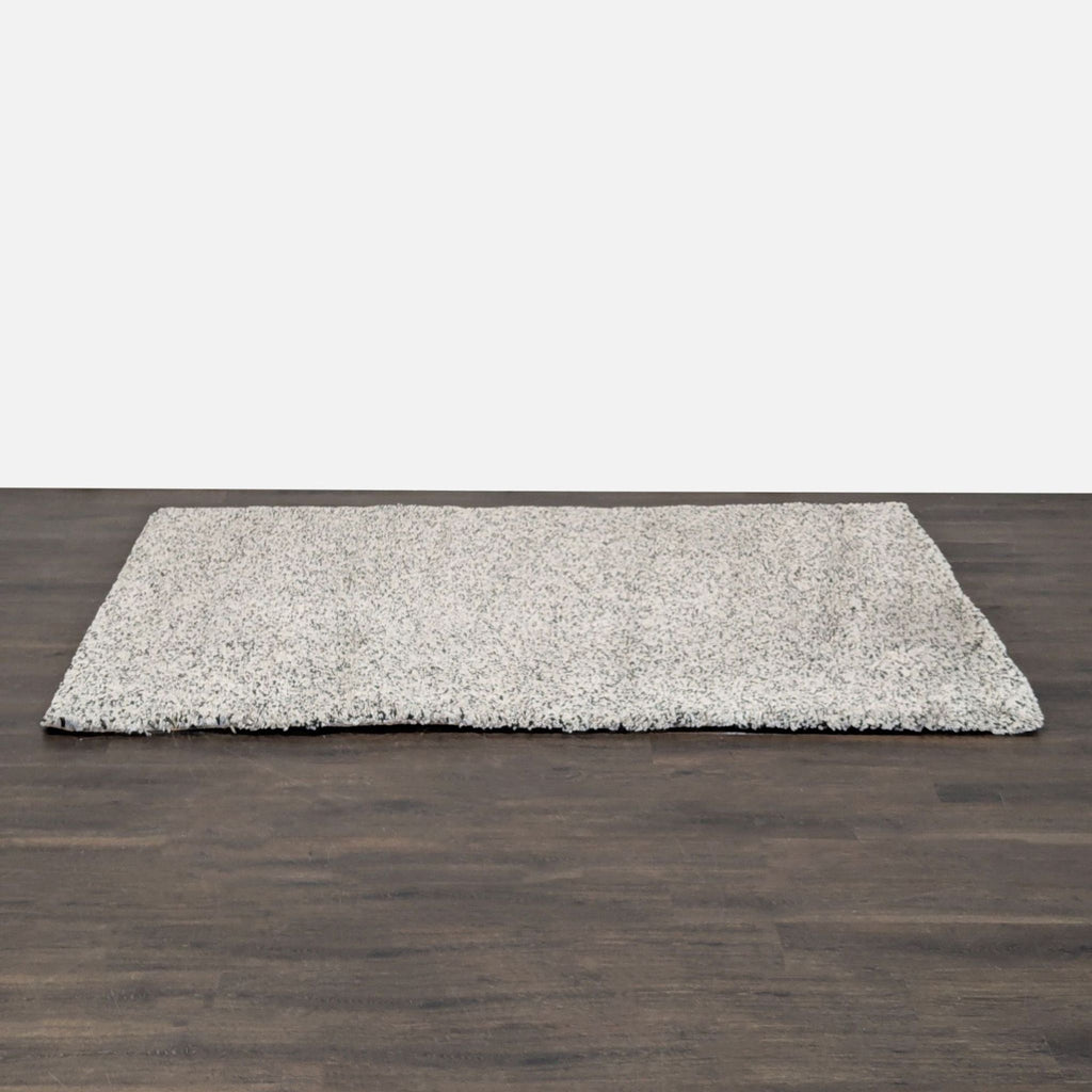 3. Ikea shaggy area rug in light gray and white speckle pattern, displayed on a wooden floor.