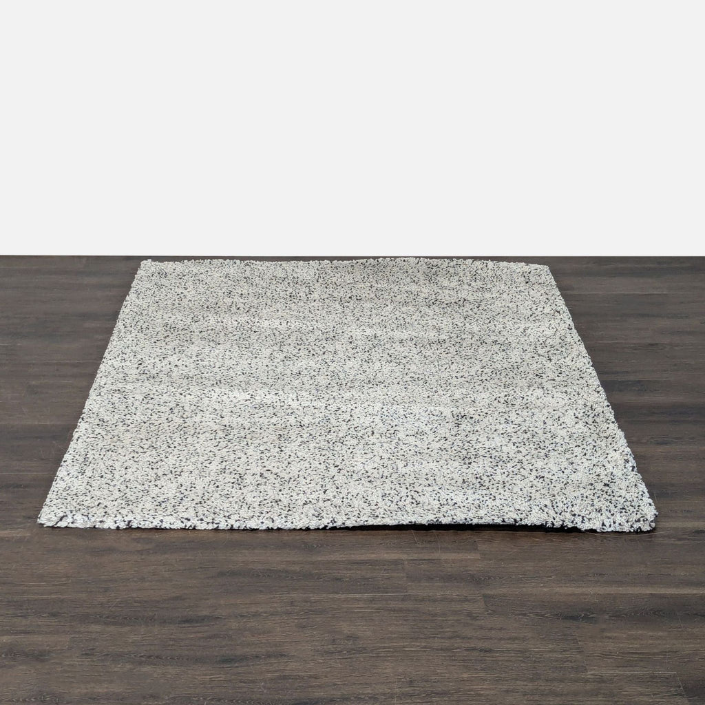 1. Ikea rectangular rug with a white and gray speckled pattern on a dark wood floor.
