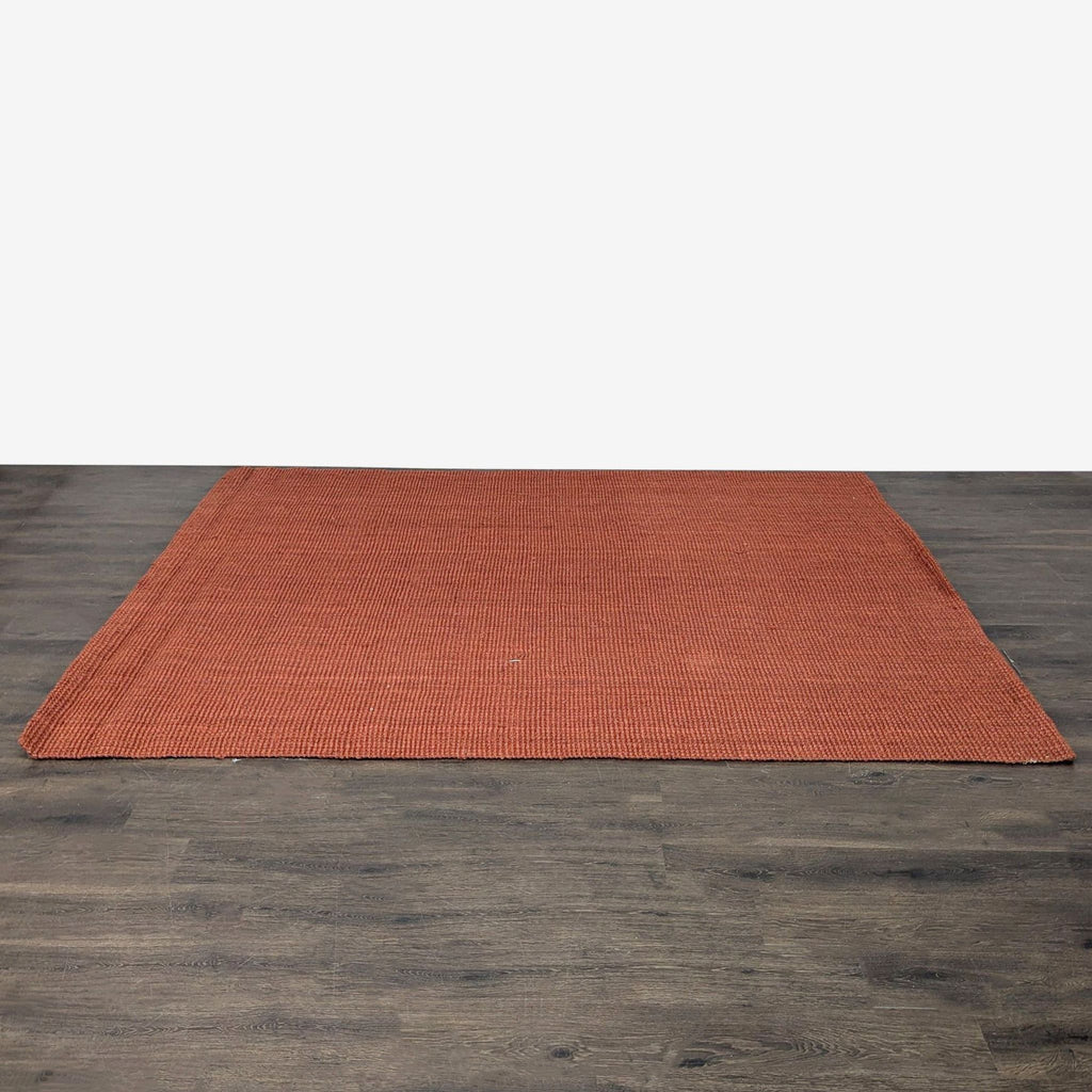 3. West Elm 5x8 ft. rust handwoven jute rug displayed flat, highlighting its simple and durable design.