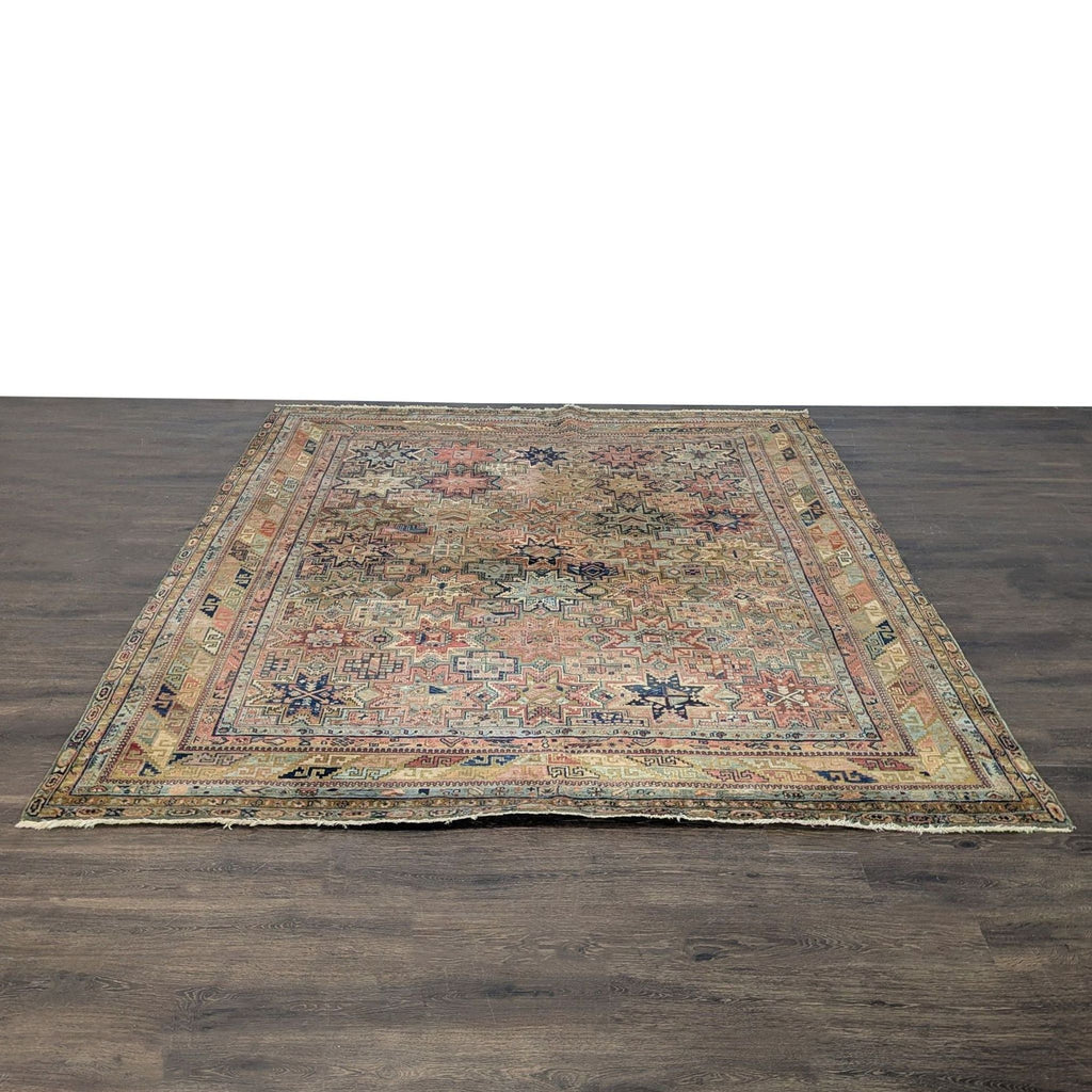 Vintage rug with geometric star motifs in warm earth tones and faded blues, reds, and yellows.