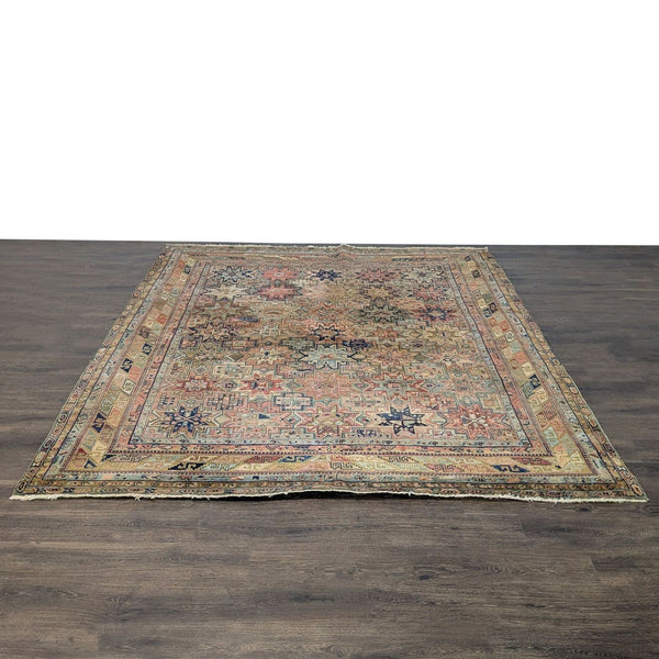 Vintage rug with geometric star motifs in warm earth tones and faded blues, reds, and yellows.
