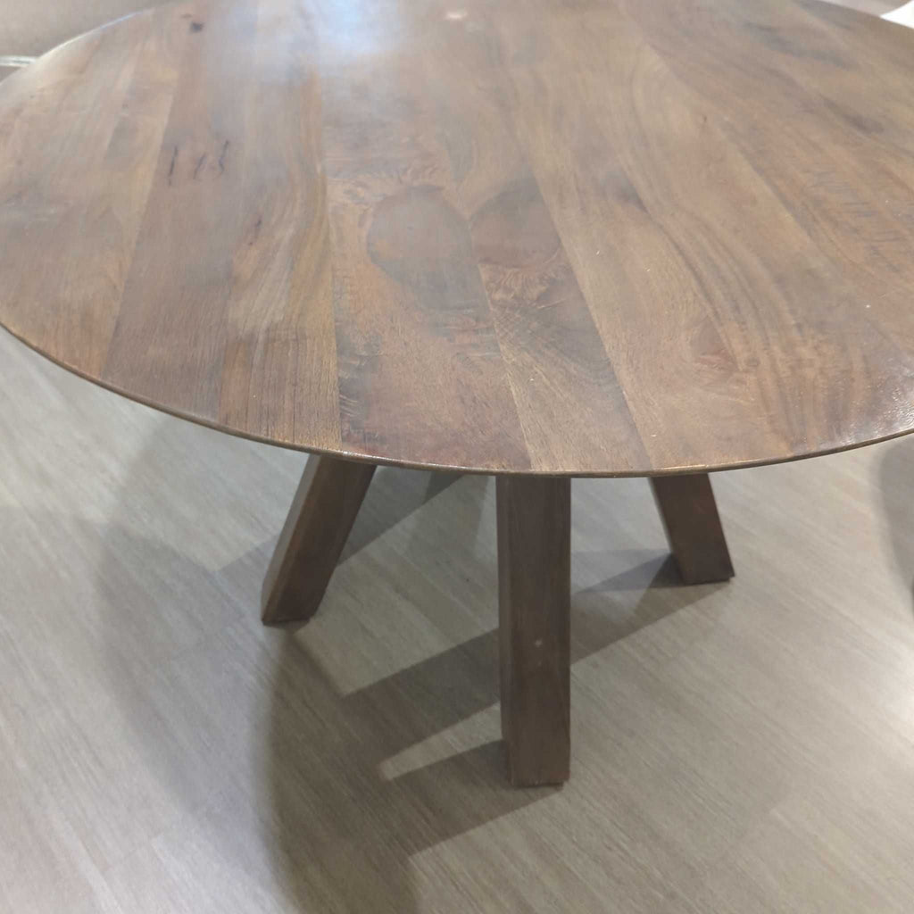 2. Close-up view of the round wooden dining table top and its angled legs, highlighting the wood grain.